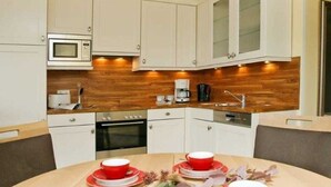 A compact kitchen with white cabinets, a microwave, and a coffee maker. - (1) 3 room apartment - sea views - apartment block "Atlantic" (Kühlungsborn)
