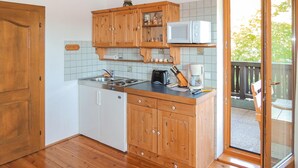 Een kleine keuken met houten kastjes, een magnetron, een broodrooster en een koffiezetapparaat.