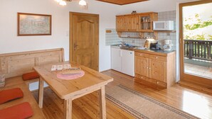 Een gezellige keuken met houten kastjes, een eettafel met rode kussens en uitzicht op het landschap.