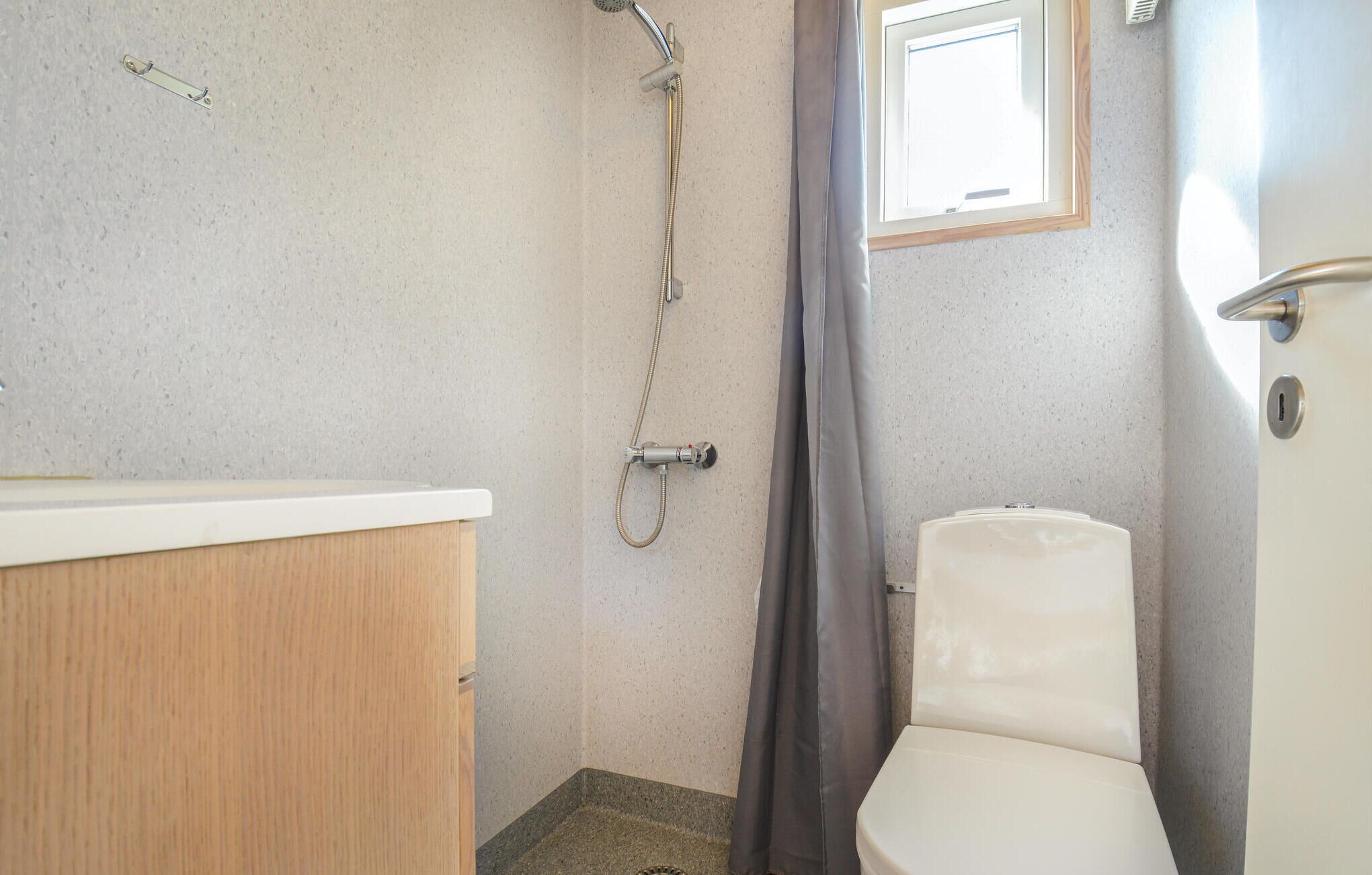 Ein Badezimmer mit Dusche, Toilette und Fenster.