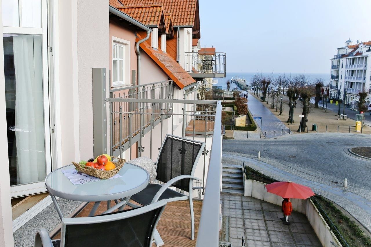 En balkong med ett bord, stolar och en korg med frukt.