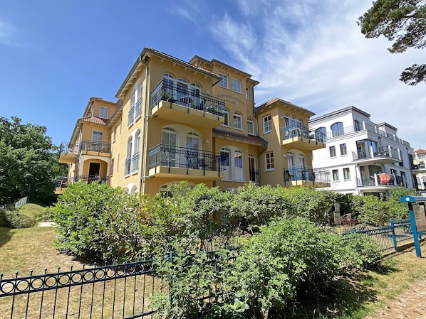 A multi-story residential building with balconies and a well-maintained garden area.