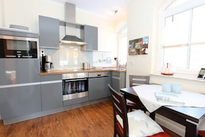 A modern kitchen with stainless steel appliances, a wooden countertop, and a dining area with a table and chairs.