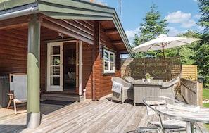 A wooden cabin with a deck, wicker furniture, and a covered outdoor seating area. - Cozy home in Væggerløse with WiFi (Væggerløse)