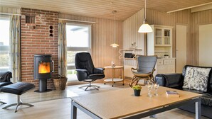 Una sala de estar acogedora con chimenea, asientos cómodos, una mesa de comedor y una zona de cocina.