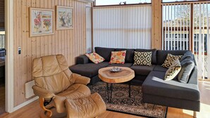 A cozy living room with a brown leather armchair, a dark grey sectional sofa with patterned cushions, and a small wooden coffee table. - Gorgeous home in Sydals with sauna (Sydals)