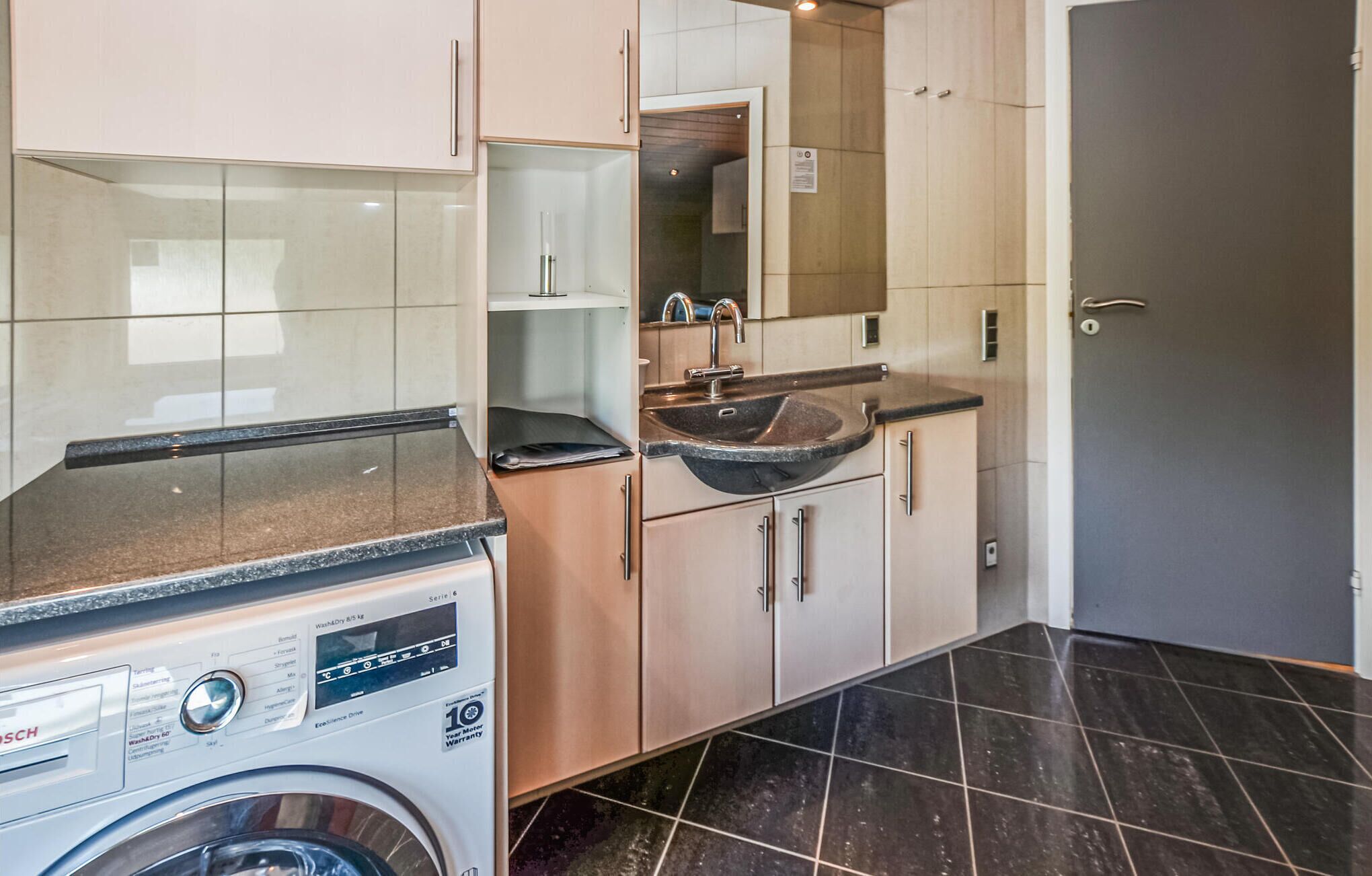 A compact kitchen with a washing machine, a sink, and cabinets.