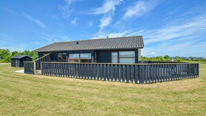 A single-story building with a tiled roof, a wooden deck, and a fenced yard. - Gorgeous home in Sydals with sauna (Sydals)