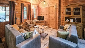 A cozy log cabin interior with two sofas, a television, and a dining table. - Cozy home in Neede with sauna (Neede)