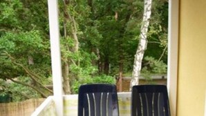 Un balcon avec deux chaises noires et une table ronde.