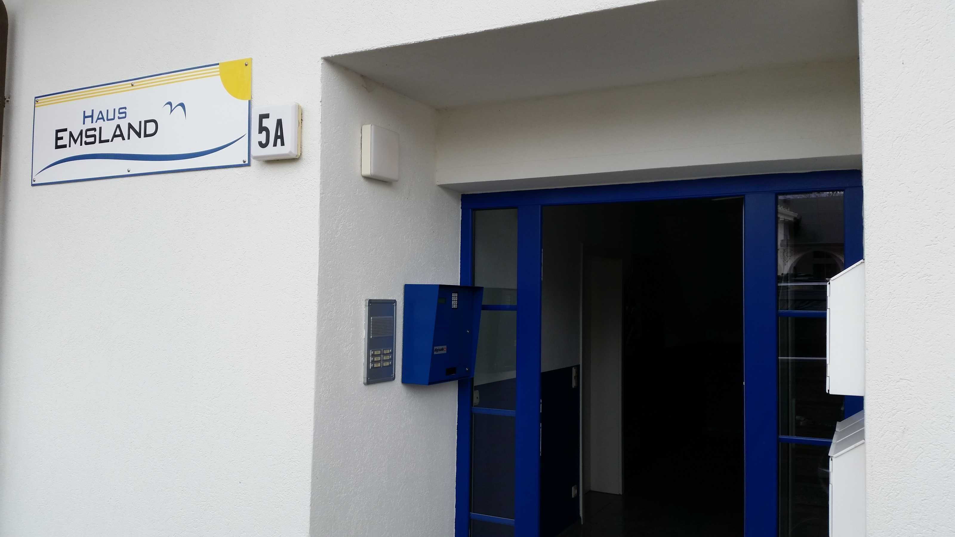 A building entrance with a sign reading "HAUS EMSLAND 5A" and a blue door.