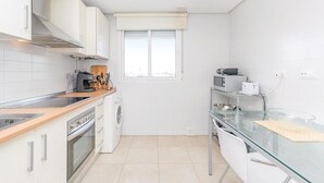 A compact kitchen with white cabinets, a built-in oven, a microwave, and a glass dining table. - 2 bedroom gorgeous apartment in Roldán (Roldán)
