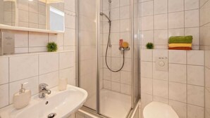 Une salle de bain équipée d’une douche, d’un lavabo, de toilettes et d’une étagère avec des serviettes.