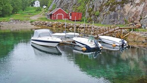 A serene lakeside scene with a red barn and a dock with several boats. - 2 bedroom stunning apartment in Sandstad (Sandstad)