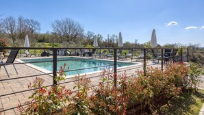 A pool area with lounge chairs and umbrellas, surrounded by vegetation. - Cozy apartment in Kanfanar (Kanfanar)