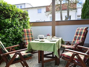 Un patio con una mesa dispuesta para tomar té, rodeado de sillas a cuadros.