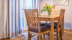 A dining area with a wooden table and chairs, a vase with flowers, and a compass artwork on the wall. - Wohnpark An der Muehle Whg Cuba1-1 .. - Cuba 1. 1 (Kühlungsborn)