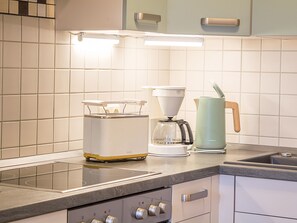 Una cucina con un piano cottura moderno, una macchina da caffè e un bollitore sul bancone.
