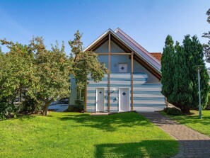 A modern house with a sloped roof, a large window, and a small door.