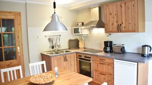 A compact kitchen with wooden cabinets, a stainless steel sink, a microwave, a toaster, and a coffee maker. - Apartment 1 - Usedom Landhaus Morgenitz (Mellenthin OT Morgenitz)