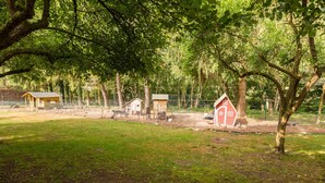 A fenced outdoor area with several small wooden structures, likely cabins or sheds, surrounded by trees. - Apartment 1 - Usedom Landhaus Morgenitz (Mellenthin OT Morgenitz)