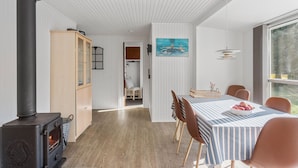 A cozy dining area with a wooden table, chairs, and a view of the outdoors through a large window. - Pet friendly home in Væggerløse with sauna (Væggerløse)