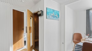 A room with white paneled walls, a wooden door, a painting, a table with chairs, and a window with curtains. - Pet friendly home in Væggerløse with sauna (Væggerløse)