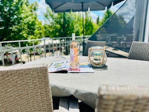 An outdoor dining area with wicker furniture, a glass candle holder, and a magazine on the table.
