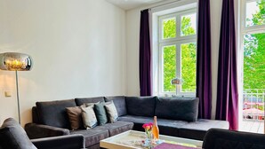 A modern living room with a sofa, a coffee table, and a view of greenery outside.