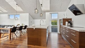 Une cuisine moderne dotée d’un îlot central, de meubles en bois et de luminaires suspendus.