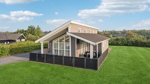 Une maison à deux étages avec un patio couvert, une cour clôturée et un ciel dégagé.