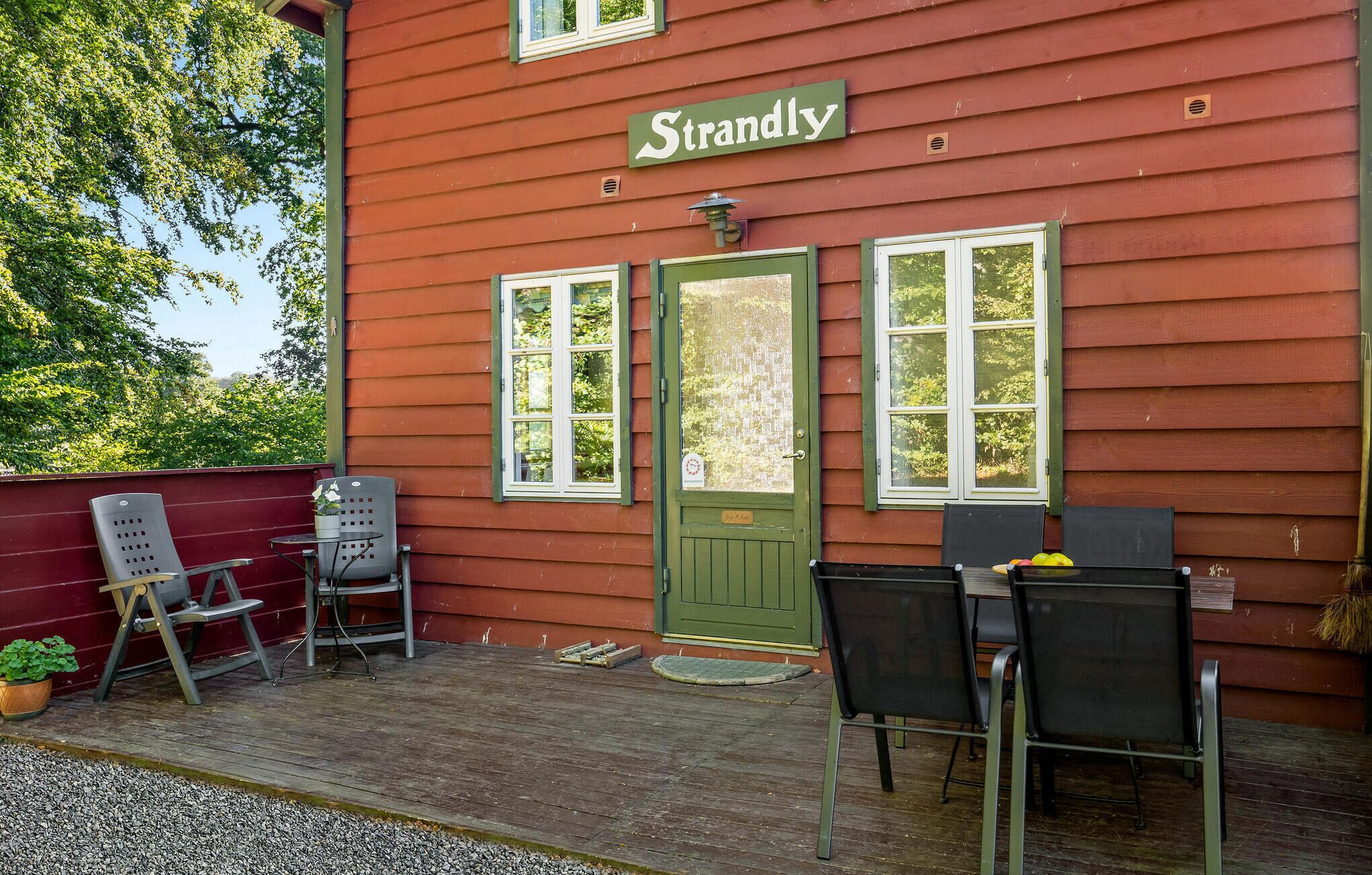 A red building with a green door and windows, labeled "Strandly".