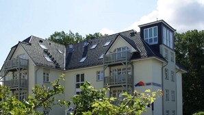 Een meerhoog gebouw met een schuin dak, balkons en een bord dat aangeeft dat het een Weststrand hotel is.