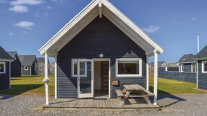 A small, dark-colored cottage with a gabled roof, a wooden deck, and a single window. - 2 bedroom beach front home in Thyborøn (Thyborøn)