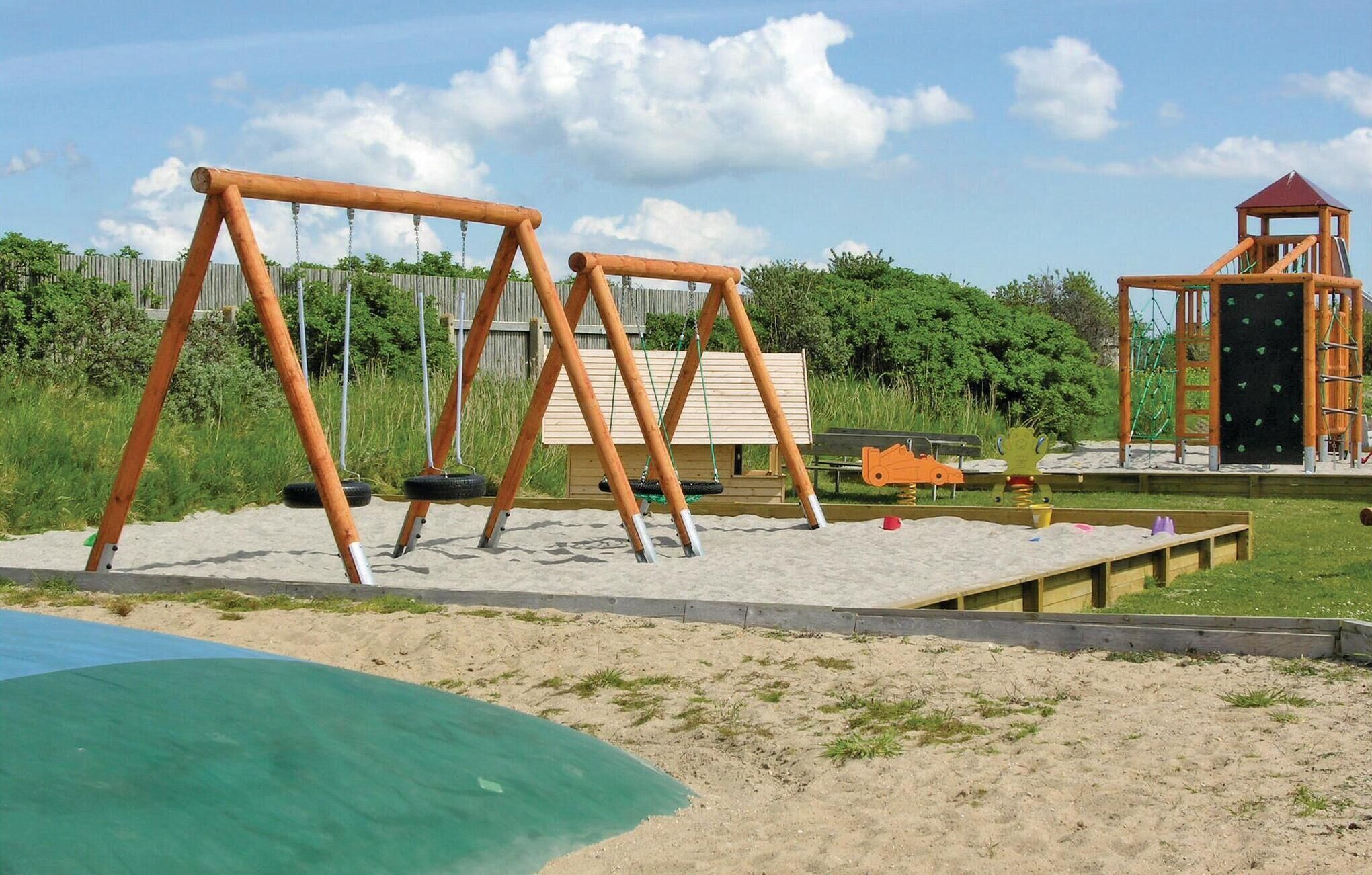 Un'area giochi con altalene, una struttura per arrampicarsi e una sabbiera.