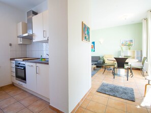 A modern kitchen with white cabinets, a built-in oven, and a stainless steel range hood.