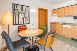 Un comedor con una mesa redonda, cuatro sillas, una lámpara y un cuadro en la pared.