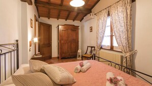 Ein Schlafzimmer mit einem Bett, Kissen, einem Holzschrank, einem Heizkörper und einem Fenster mit Vorhängen.