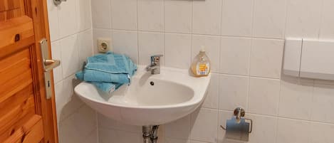 A bathroom with a white sink, a mirror, a wooden door, and a toilet.