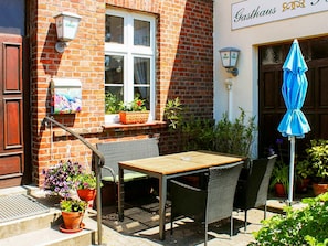 An outdoor seating area with a table and chairs, a blue umbrella, and potted plants. - Double room 1 - Rankwitzer Hof (Rankwitz)