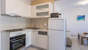 Eine moderne Küche mit weißen Schränken, einem Backofen, einer Spülmaschine, einem Kühlschrank und einer Kaffeemaschine.