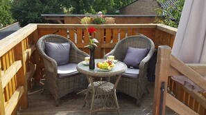 A wooden deck with wicker chairs and a table set with fruit and cups. - Apartment 2 OG - Apartments Villa Waldbrik - Zempin (Zempin)