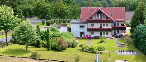 Un bâtiment à deux étages, avec un toit rouge, entouré d’une pelouse bien entretenue et d’arbres.