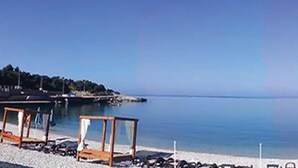 Une plage avec une structure en bois, un ciel dégagé et une eau calme.