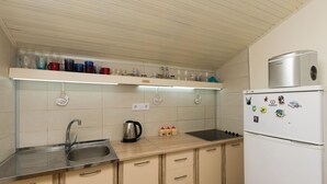 Une cuisine équipée d’un évier en acier inoxydable, d’une bouilloire, d’un réfrigérateur et d’un plan de travail sur lequel on trouve des bocaux en verre et une machine à café.