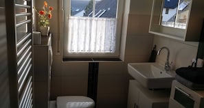 A compact bathroom with a window, a sink, and a toilet.