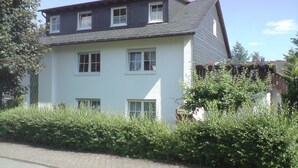 A two-story building with multiple windows, a garage, and a paved driveway. - Apartment Debray 2 ****, 78 sqm - Apartments Debray **** (Winterberg)