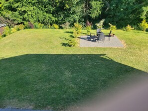 Une pelouse bien entretenue avec un espace patio aménagé et doté de mobilier d’extérieur.