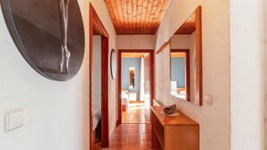 Un corridoio con soffitto in legno, uno specchio e pavimento piastrellato.