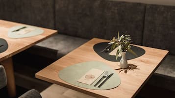 A restaurant setting with tables set for dining, each with a placemat, cutlery, and a small vase with flowers.